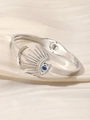 Nahaufnahme von silbernem Evil Eye Armreif mit blauem Stein auf beigem Seidenstoff - Silber