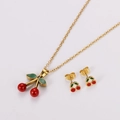 Detail view of gold cherry jewelry set with red and green enamel on white background - Medium