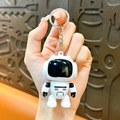 White and black cartoon astronaut robot keychain SKU variant held in hand - White