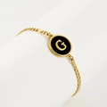 18K gold plated Figaro chain bracelet with black enamel medallion featuring letter G - Letter G / Gold/Black
