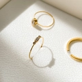 Detalle de anillos dorados con diseño de trébol de circonitas sobre cuero blanco fino - US 6 / Triple Circonita Ovalada