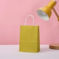 Detail of mustard yellow kraft paper gift bag with white rope handles on a desk - 15*11*6 / Gold