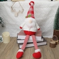 Kerstkabouter met lange benen en rood-witte ruitjesmuts zittend op een stapel boeken - Gezichtsloze Gnoom Hart Stijl