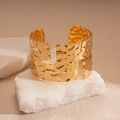 Nahaufnahme der goldenen Manschette mit Hammerschlag-Textur und geometrischen Ausschnitten - Gold