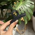 Pince à cheveux noire brillante élégante avec ressort doré sur fond de feuille - Noir transparent