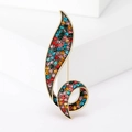 Broche rétro noire sertie de cristaux colorés au design de feuille sur fond blanc - Coloré