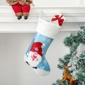 Blauwe kerstsok met kabouterprint en witte pluche rand hangend aan een open haard - Gnoom met geschenkdoos