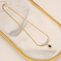 Golden snake chain necklace with square emerald zircon pendant on marble tray - Necklace / Gold