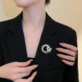 Detailed view of a gold floral wreath brooch with pearls and a crystal butterfly on a blazer - Gold Butterfly Ring