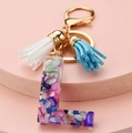 Macro shot of resin letter L keychain with colorful gravel and blue-white tassels - L