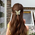 Pince à cheveux papillon vert menthe mat présentée sur une coiffure demi-queue bouclée - Vert