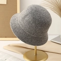 Close-up of a warm gray knitted bucket hat for women displayed on a golden metal stand - M (56-58cm) / Gray