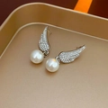 Dettaglio degli orecchini ad ala con strass e perle bianche su un vassoio dorato - Orecchini (Perno in argento 925 - Argento)