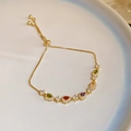 Close-up of a gold bracelet featuring multi-colored teardrop gems and adjustable drawstring - Gold Multicolor