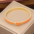Dettaglio di un bracciale a farfalla dorato con smalto arancione e pietre di zircone - Arancione