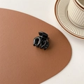 Detail of a small black glossy hair claw clip placed on a leather mat with a ceramic cup - Glossy Black (Medium Approx. 3.5cm)