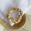 Elegant champagne satin scrunchie with soft pleated texture on decorative tray - Khaki