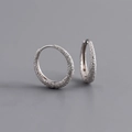 Dettaglio orecchini a cerchio in argento con finitura sabbiata scintillante su grigio - Argento 925 / Oro Bianco