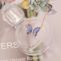 Elegant gold chain necklace with blue crystal butterfly pendant on decorative perfume bottle - Sapphire Blue
