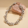 Primer plano de collar de perlas barrocas con pedrería sobre una piedra con textura - Collar - Dorado