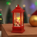 Close-up of red Christmas lantern with Santa Claus pattern and warm LED candlelight - Red Santa Claus