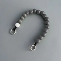 Close-up of gray and white wooden beads phone strap with metal ring clasps on gray background - Phone Chain #6 (Grey Beads)