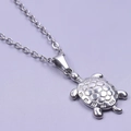 Détail d'un pendentif tortue argenté avec texture de carapace sur une chaîne en O - Collier / Argenté