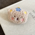 Macro view of a cute khaki flocked bear brooch with soft plush texture and embroidery - Coffee Bear With Hat