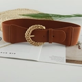 Detail of brown wide elastic waist belt with a twisted gold round buckle on a magazine - Brown