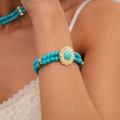 Close-up of bohemian double-layer turquoise beaded bracelet with golden flower charm - Blue Double Layer Turquoise Bracelet