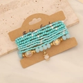 Detail view of multi-layer bohemian beaded bracelets with turquoise and gold crystal charms - Green