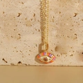 Detaillierte Ansicht der Evil Eye Halskette mit rosa Zirkon und Goldfinish auf Stein - Bunt