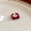 Close-up of deep red velvet bow ring on a ceramic plate with adjustable opening - Alloy/Flocking / Red Bow Open Ring