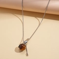 Détail de chaîne argentée avec pendentif sphère en résine brune et accents élégants - Collier Géométrique Marron