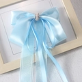 Dettaglio del fermaglio a fiocco azzurro in raso con perle e lunghi nastri in chiffon - Blu
