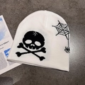 Close-up of knitted beanie with white skull, crossbones and spider web graphic patterns - M (55-59cm) / White