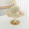 Close-up of hand-woven straw hat with wavy brim and delicate floral ribbon accents - Hat / Beige