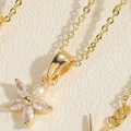 Macro detail of a gold flower pendant necklace featuring clear marquise-cut zircon petals - Flower Necklace