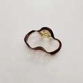 Macro detail of wave-shaped hollow hair claw clip with gold frame and dark brown finish - Brown
