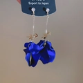 Detailansicht langer Goldohrringe mit geschichteten, matt dunkelblauen Acrylblütenblättern - Silbernadel-Blau