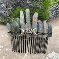 Detail of natural raw crystal hair comb with silver triple moon pentagram on mossy rock - Kyanite Black Wire Silver Moon