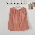 Detail of coral pink cotton apron featuring large utility pockets and pleated waist texture - Orange Red