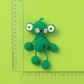 Handmade green knitted strawberry doll keychain with measuring rulers for size reference - Dangling Leg Frog Doll
