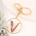 Close-up of golden keychain with colorful rhinestone letter V pendant and alloy finish - Letter V