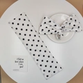 Detail eines weiß-schwarzen Polka-Dot-Haarknotenmachers und Haargummis auf Tisch - Weiß Gepunktet
