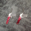 Detailed view of silver pistol earrings with realistic red blood splatters and ear hooks - Handgun