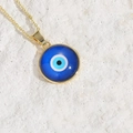 Golden cross chain necklace featuring a blue resin Evil Eye pendant on stone surface - Dark Blue