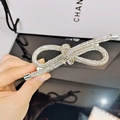 Macro shot of silver bow hair clip with sparkling rhinestones and knot design detail - White Zircon Style