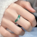 Silver open ring with row of sparkling emerald green zircons on a soft textured background - Silver Row Set Green Gemstone