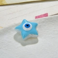 Macro di una perla a stella in resina con malocchio azzurro su un piatto di ceramica bianca - Azzurro
